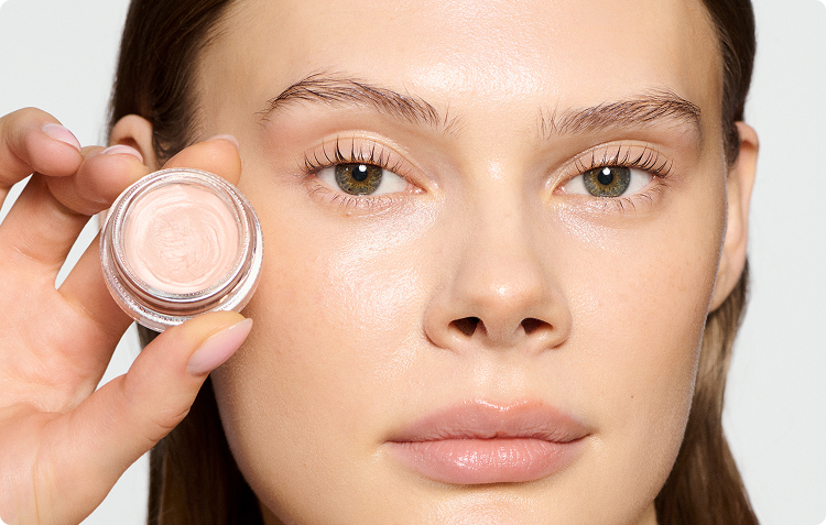 Woman wearing wake me up cream and holding the jar